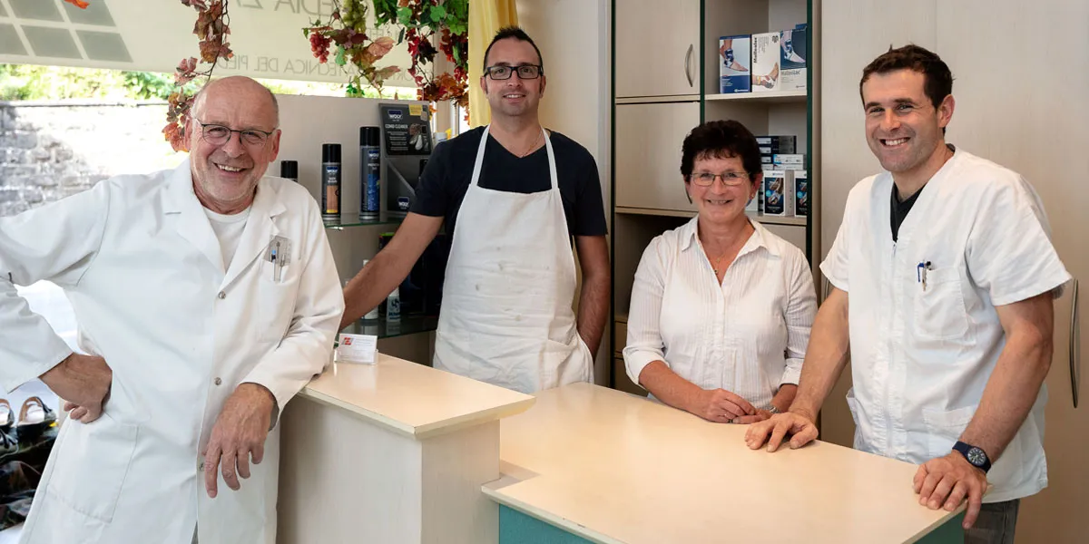 Il team di Zanini Ortopedia in negozio, dietro il bancone: quattro persone sorridenti